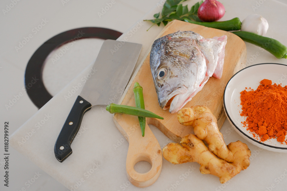 Fresh snapper fish on a wooden cutting board in a kitchen with a knife nearby