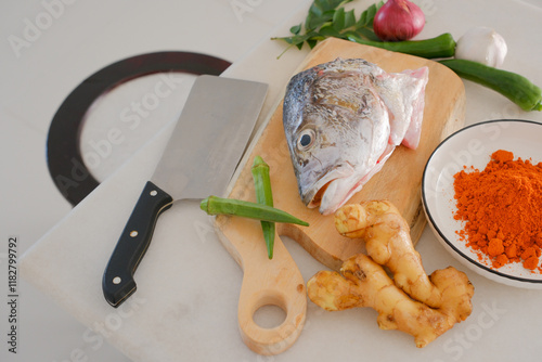 Obraz na płótnie Fresh snapper fish on a wooden cutting board in a kitchen with a knife nearby w salonie