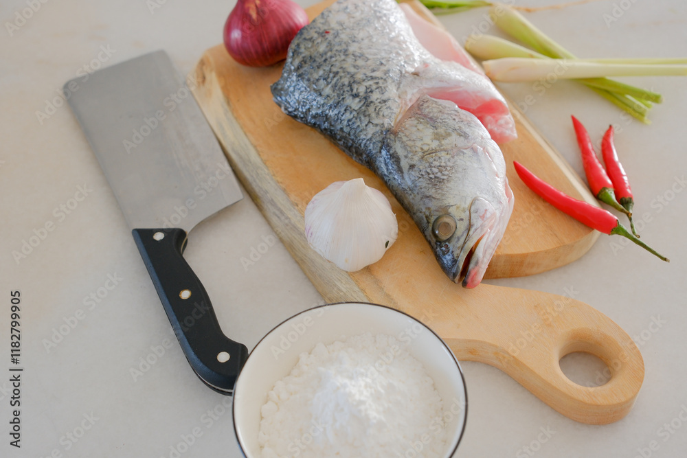Fresh snapper fish on a wooden cutting board in a kitchen with a knife nearby