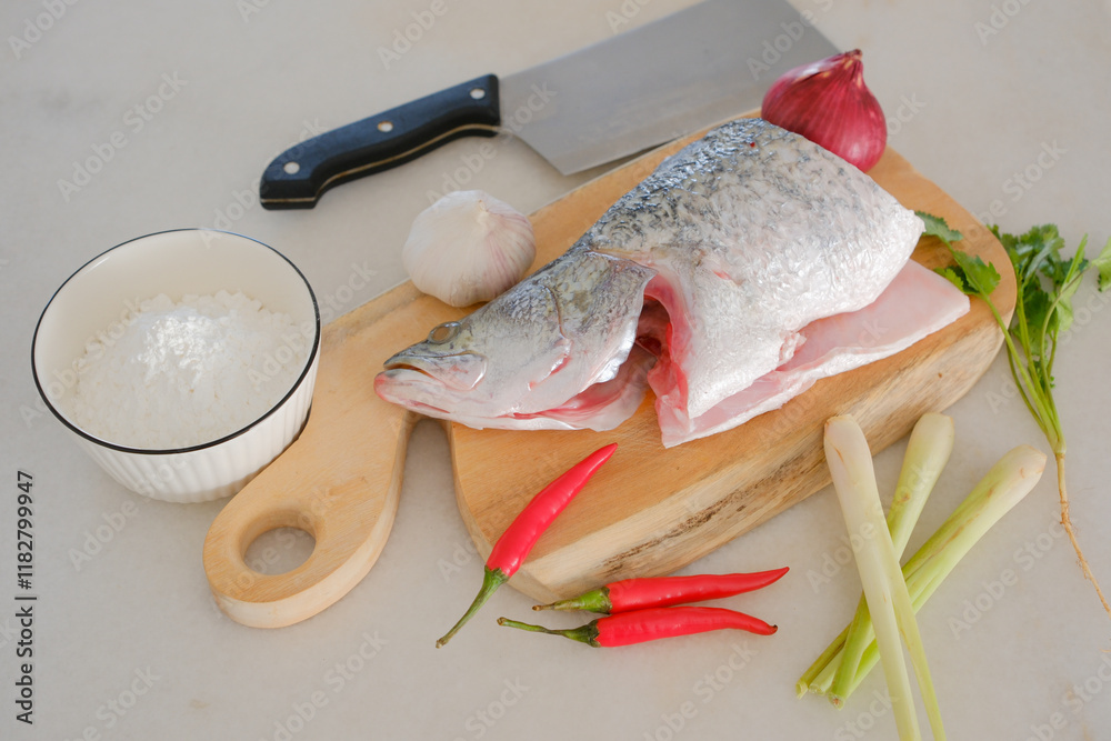 Fresh snapper fish on a wooden cutting board in a kitchen with a knife nearby