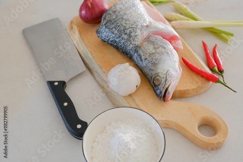 Obraz na płótnie Fresh snapper fish on a wooden cutting board in a kitchen with a knife nearby w salonie