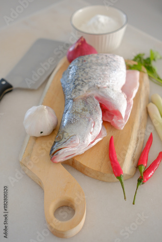 Obraz na płótnie Fresh snapper fish on a wooden cutting board in a kitchen with a knife nearby w salonie
