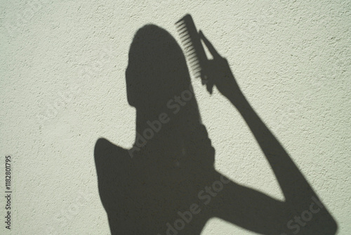 A person styling their hair against a light-colored wall