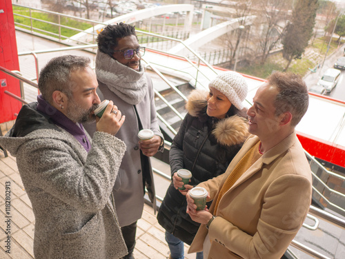 Four office workers taking a coffee break in a lively business district. The group consists of one Black male, a woman, and two Hispanic individuals. They are looking at each other and engaging in
