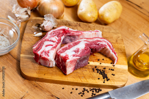 Raw beef brisket served with onions and peppercorns at table photo