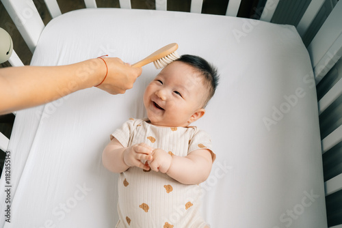 A mom brushes the baby's hair in the crib. photo