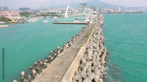 TAIWAN, CHINA - JANUARY 7, 2025: Coastal view showcasing breakwater structure along the shoreline with boats and city skyline