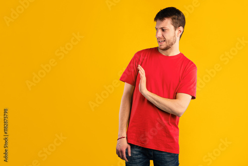 Keep Distance, Don't Stay Close To Me. Displeased young guy with disgusted facial expression raising hand, showing stop gesture with palm to the side, standing isolated over blue studio background photo