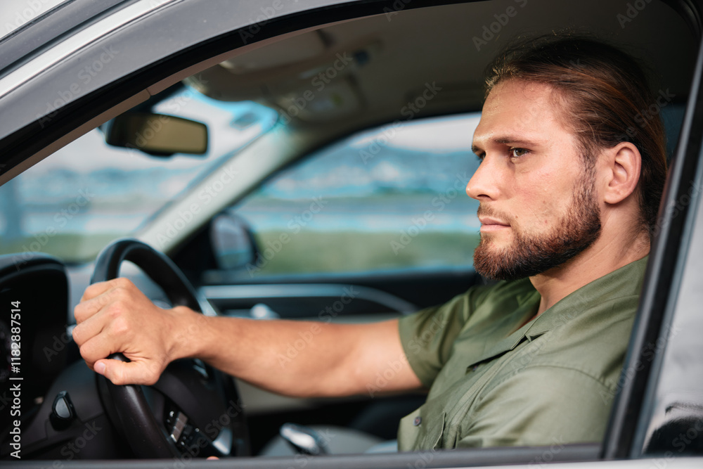 Man driving a modern car, focused and serious expression, showcasing determination and confidence in an urban setting