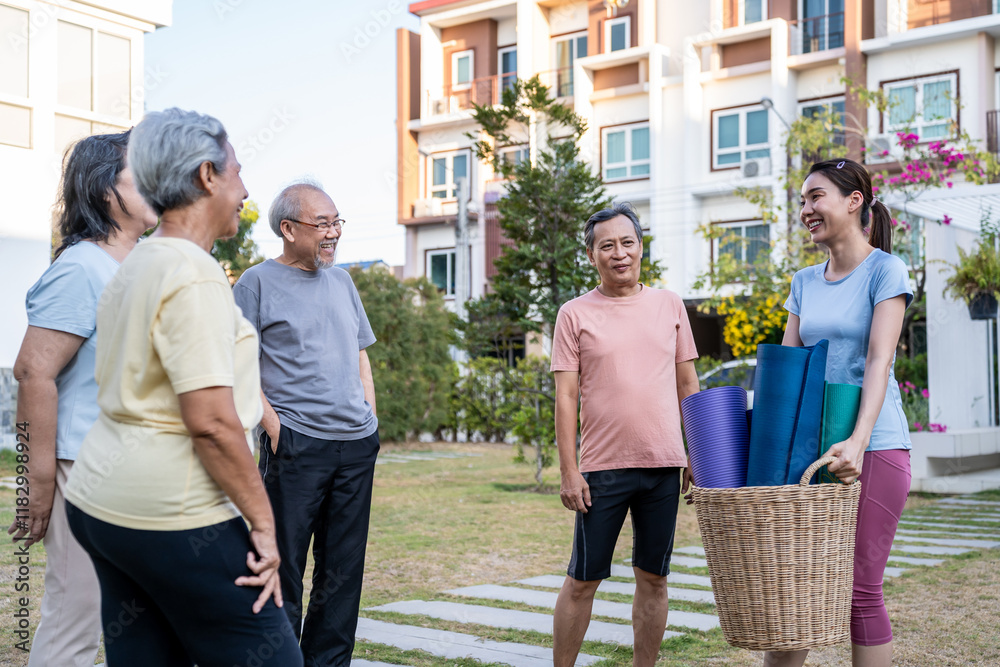 Naklejka premium Group of elderly people holding exercise mat with trainer in the garden.