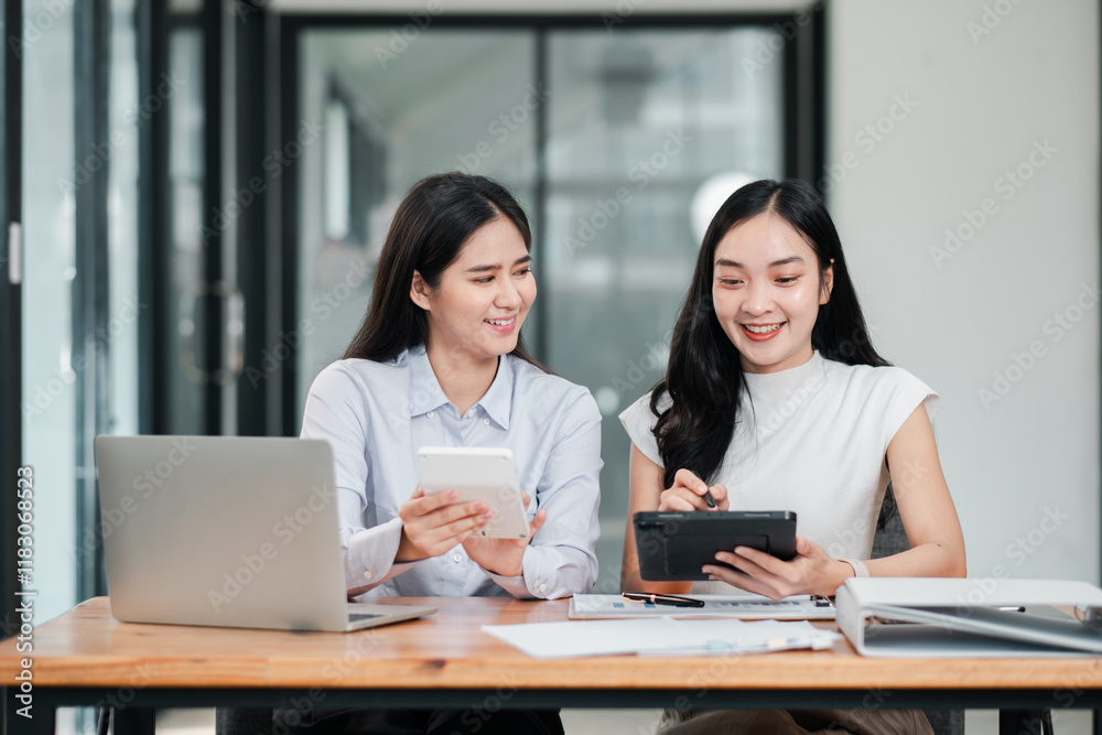 Two businesswomen working together in a contemporary office, using digital tablets and laptops, showcasing teamwork and technology. Two businesswomen working together in a contemporary office, using digital tablets and laptops, showcasing teamwork and technology.