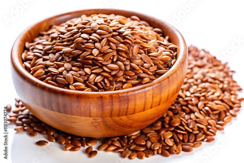 A wooden bowl filled with brown flax seeds sits on a white surface, with some seeds scattered around it.