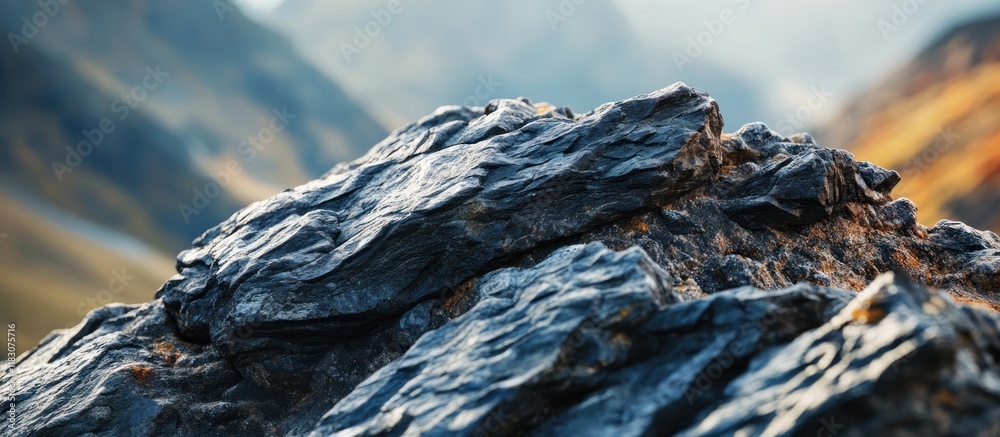 Close-up of dark, rough-textured rocks against a blurred mountain backdrop. Close-up of dark, rough-textured rocks against a blurred mountain backdrop.