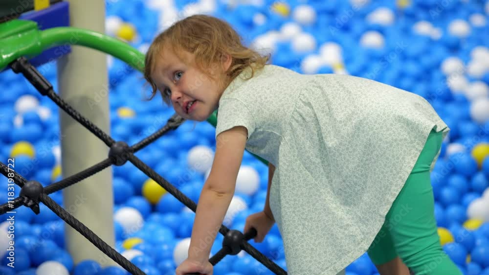Cute toddler girl climbing rope bridge in play area Cute toddler girl climbing rope bridge in play area
