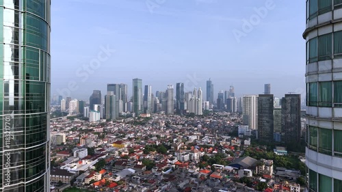 Aerial view of Jakarta skyline with hazy sky. Drone footage rising up with between skyscrapers with view of Indonesian capital cityscape. photo