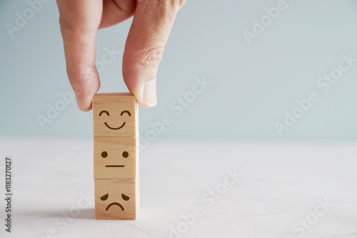 Hand choosing happy smile face wooden block, good feedback rating and positive customer review, mental health assessment, child wellness,world mental health day, think positive, compliment day concept
