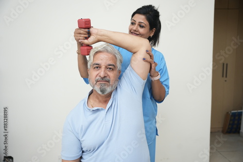 Indian physiotherapist help senior man with dumbbell exercise to recover from injury at health center. Rehab fitness for mature adult patients concept, rehabilitation.