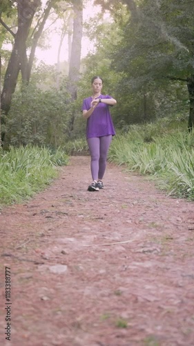 Latin woman checking smartwatch pulse while walking in park