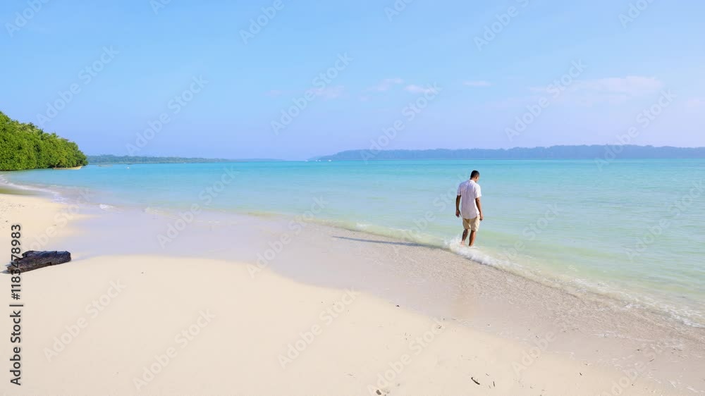 isolated man enjoying at pristine sea waves at white sand beach at morning from flat angle video is taken at Radhanagar Beach at Havelock Island in the Andaman and Nicobar Islands.