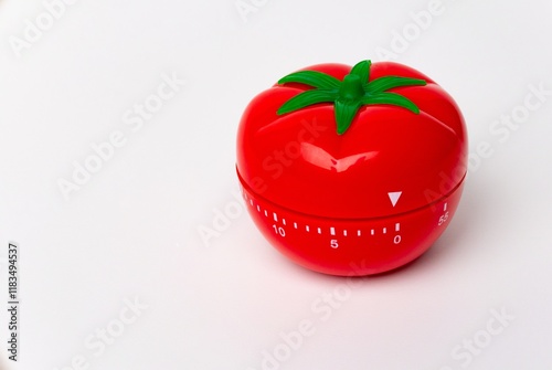 Close up view of mechanical tomato shaped kitchen clock timer for cooking and studying. Used for pomodoro technique for time & productivity management. Isolated on white background, set at 5 minutes.