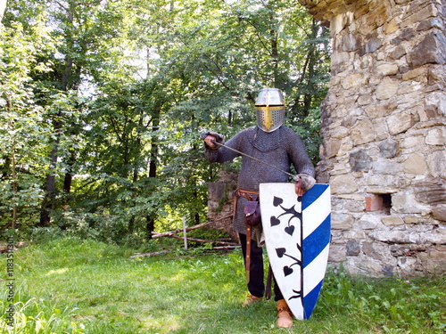 Ritter in Pose mit Schwert und Schild vor Burgmauer im Park photo