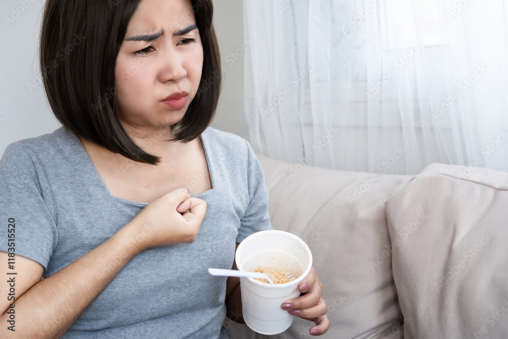 Asian woman suffering from bloating, indigestion after eating noodles, junk food Asian woman suffering from bloating, indigestion after eating noodles, junk food