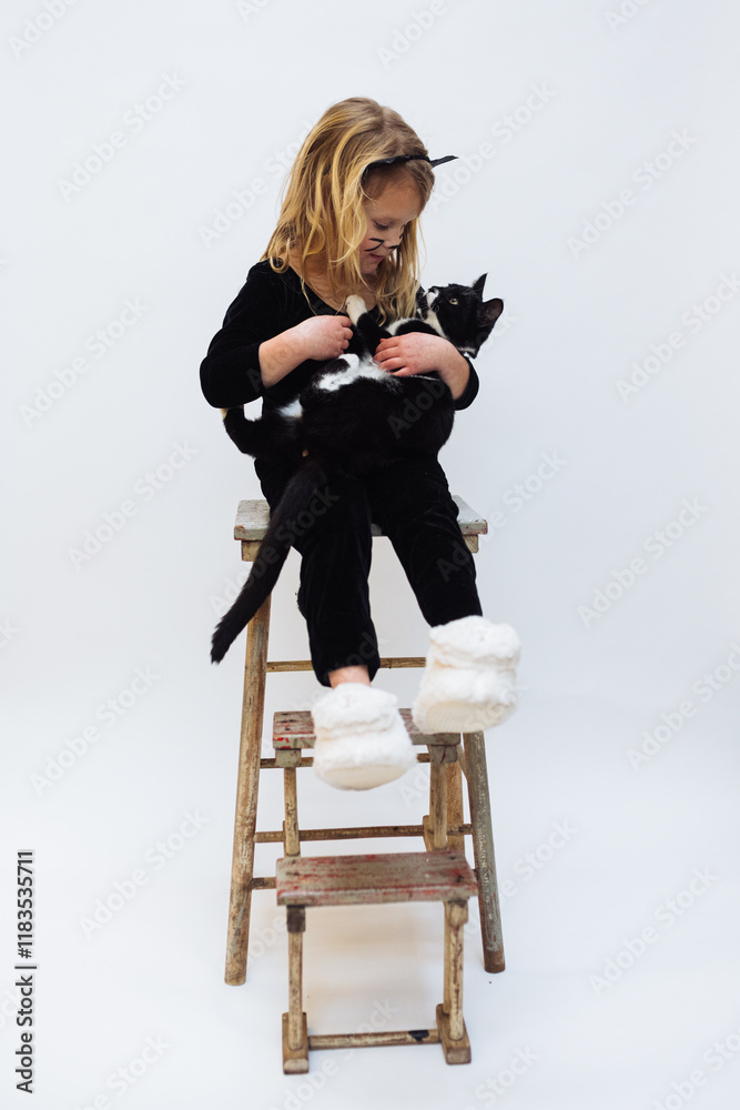 Fototapeta premium Young girl age 4-6 holding tuxedo kitten cuddling