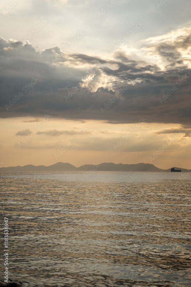 Sunset over calm sea with mountain silhouette Sunset over calm sea with mountain silhouette
