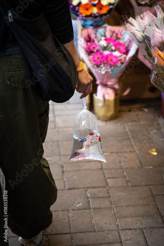 Woman carrying a fish in plastic bag walking at flower market photo