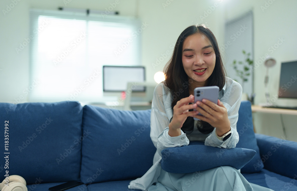 Happy freelancer woman is working remotely from home, sitting on comfortable sofa and using modern smartphone, browsing internet or chatting with friends Happy freelancer woman is working remotely from home, sitting on comfortable sofa and using modern smartphone, browsing internet or chatting with friends