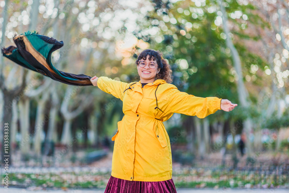 Φωτογραφία Happy young woman wearing yellow raincoat enjoying wind in autumn park