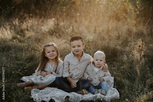 Beautiful portrait of three siblings sitting outside in brassy field