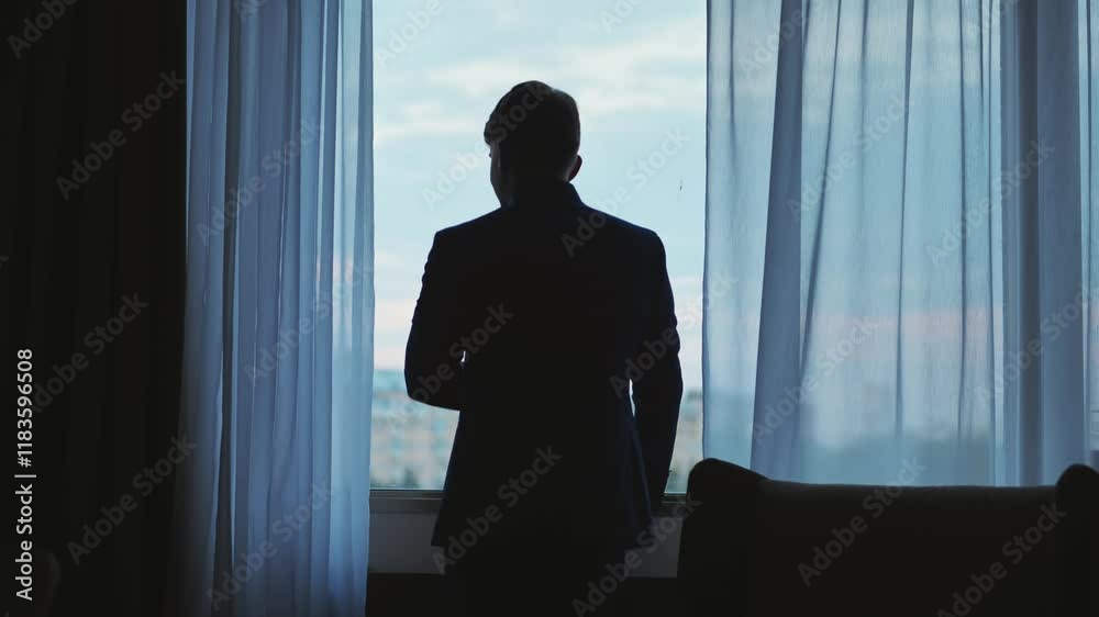 Groom looking thoughtfully out the window on his wedding day, getting ready for the ceremony Groom looking thoughtfully out the window on his wedding day, getting ready for the ceremony