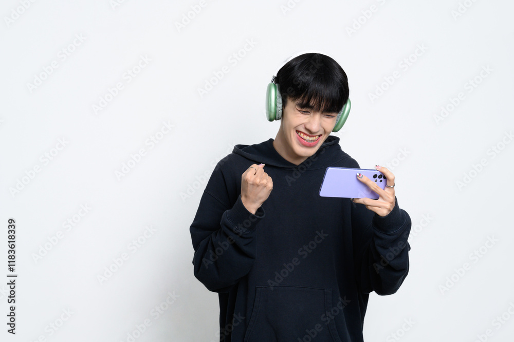 Happy man wearing headphones celebrating a gaming victory on smartphone Happy man wearing headphones celebrating a gaming victory on smartphone