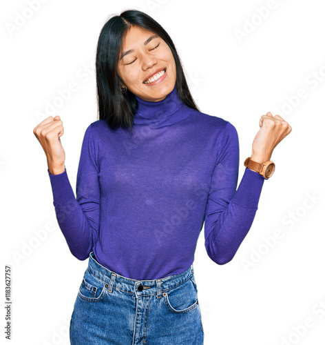 Beautiful young asian woman wearing casual clothes very happy and excited doing winner gesture with arms raised, smiling and screaming for success. celebration concept.