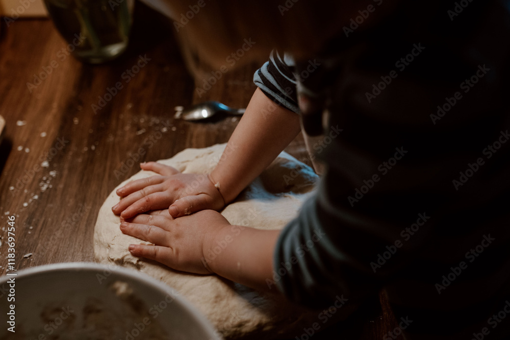 Fototapeta premium Kind knetet Pizzateig und hilft beim Backen in der Küche