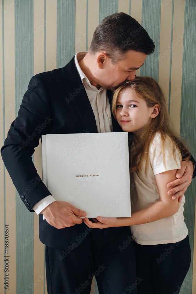 A dad and daughter hold a photo book in a white leather cover A dad and daughter hold a photo book in a white leather cover