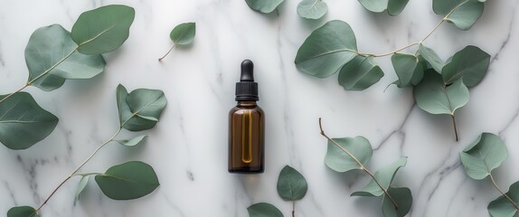 Flat lay of a glass dropper bottle surrounded by eucalyptus leaves on a marble surface