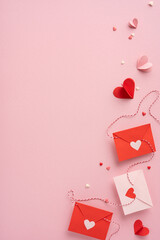 Red and white vertical envelopes with heart cutouts placed on a pink background, symbolizing love and affection. Ideal for Valentine's Day themes