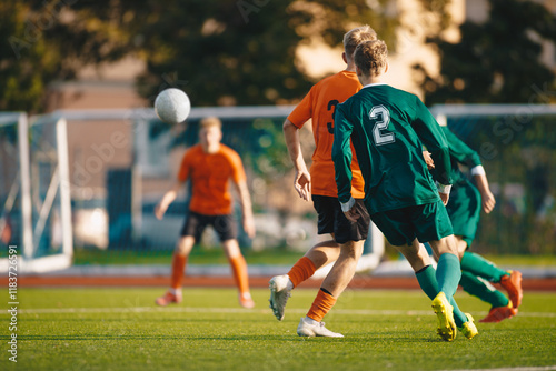 Soccer football players kick a ball towards a goal during a match in the soccer stadium. Youth football teams in a game. Footballers in action on the tournament game. Adult football competition