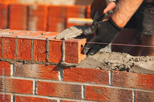 Close-up of Skilled bricklayer constructs a sturdy wall using red bricks and mortar at a construction site