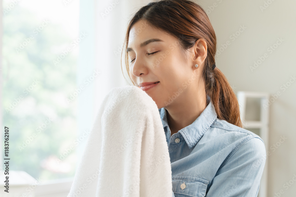 A woman smells freshly laundered clothes with a dreamy expression. A woman smells freshly laundered clothes with a dreamy expression.