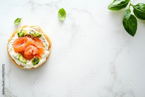 Tasty bagel topped with cream cheese salmon and avocado on a white marble surface Room for text