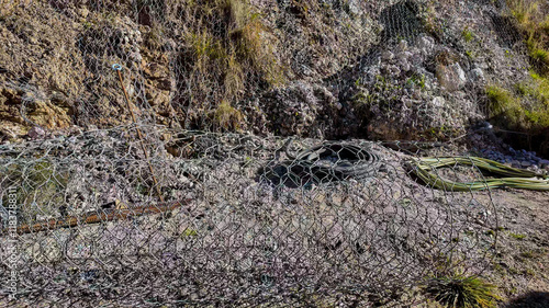 A rocky hillside with erosion control mesh and cables illustrates infrastructure erosion prevention concepts in arid environments