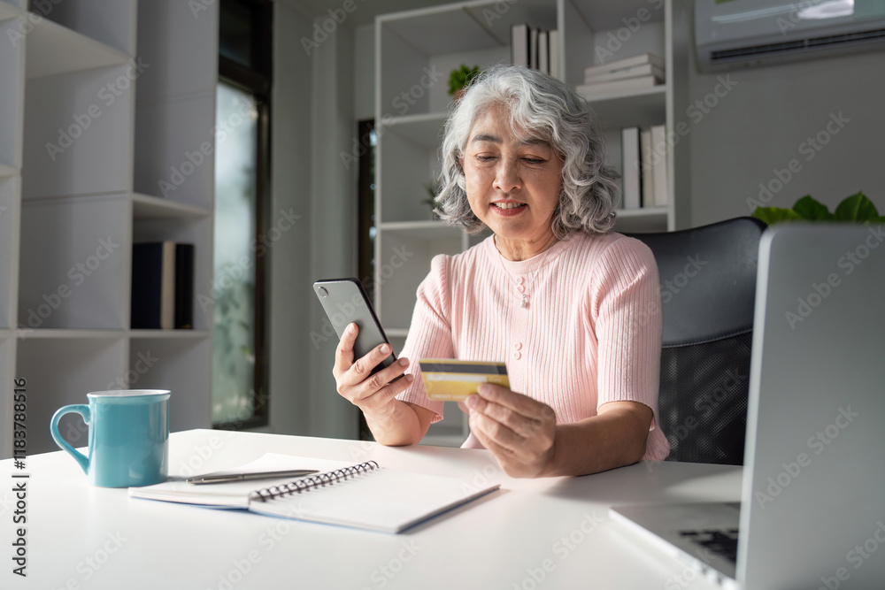 Senior woman using smartphone for online shopping while holding a credit card at home office Senior woman using smartphone for online shopping while holding a credit card at home office