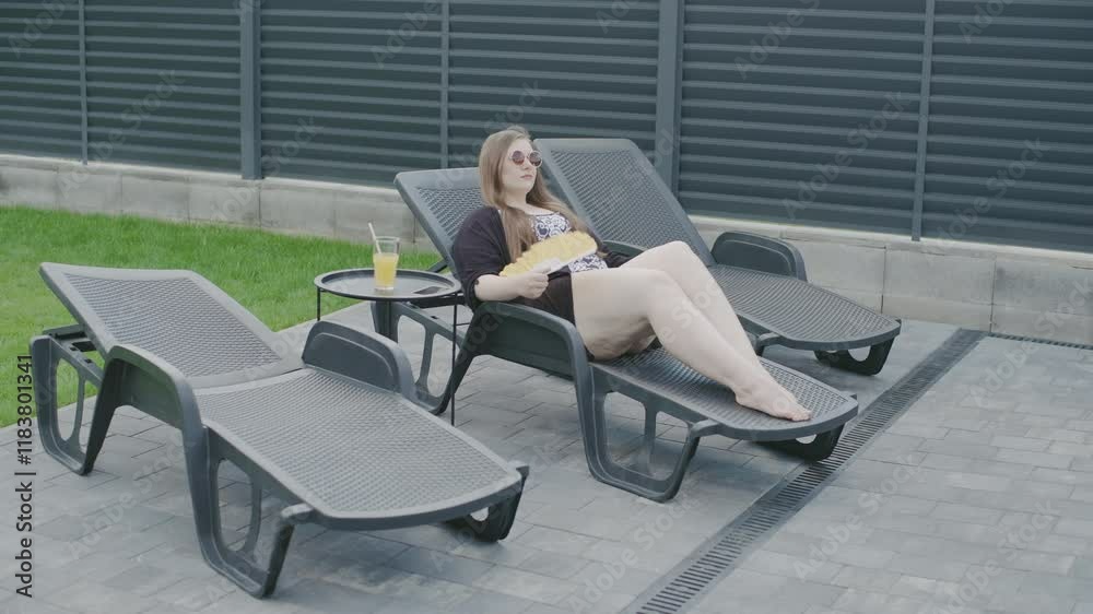Slow motion of a woman relaxing by the pool while enjoying a drink and sunbathing in a business-friendly environment Slow motion of a woman relaxing by the pool while enjoying a drink and sunbathing in a business-friendly environment