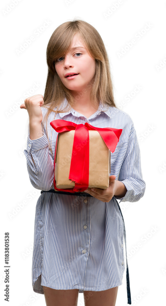 Young blonde toddler holding a present pointing with hand and finger up with happy face smiling Young blonde toddler holding a present pointing with hand and finger up with happy face smiling