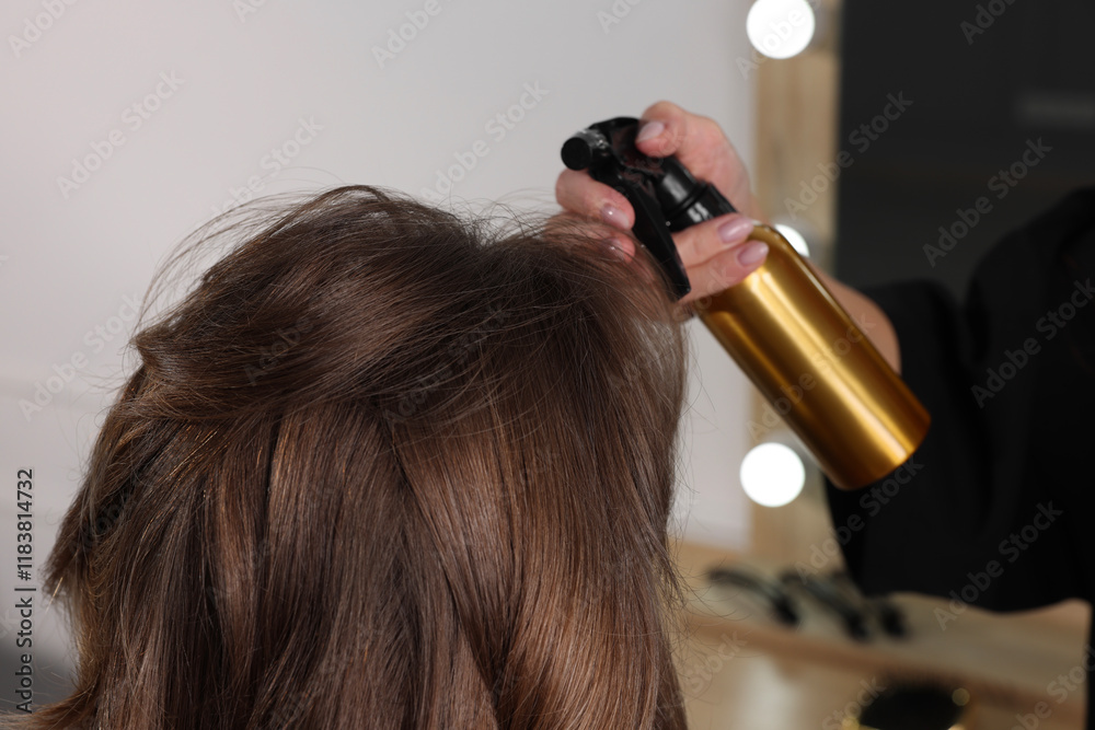 Fototapeta premium Hairdresser using spray while making stylish haircut in salon, closeup