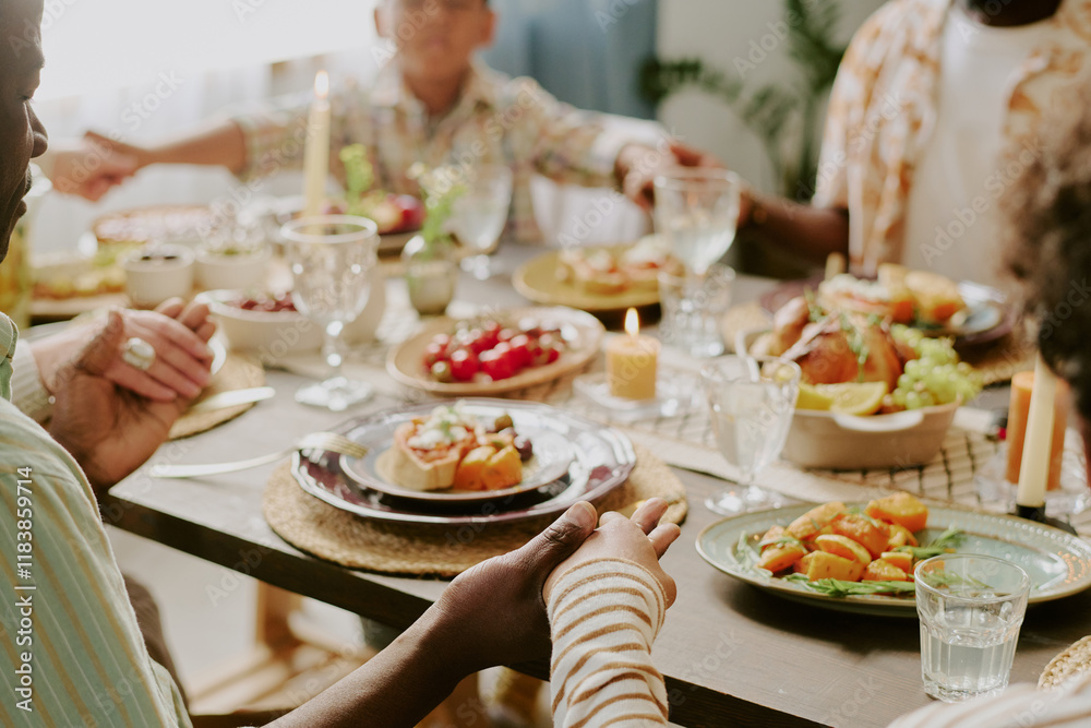Medium close up of unrecognizable hands of family members holding each other while praying before festive dinner Medium close up of unrecognizable hands of family members holding each other while praying before festive dinner