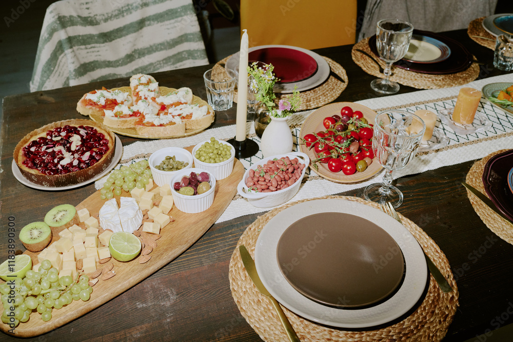 High angle shot of old wooden table with oval cheese plate, dessert and snack, table served with polished kitchenware and illumed with camera flash High angle shot of old wooden table with oval cheese plate, dessert and snack, table served with polished kitchenware and illumed with camera flash